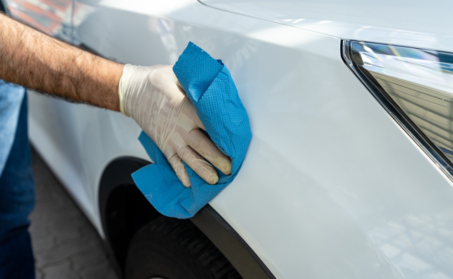 Man hand cleaning the car with blue towel.