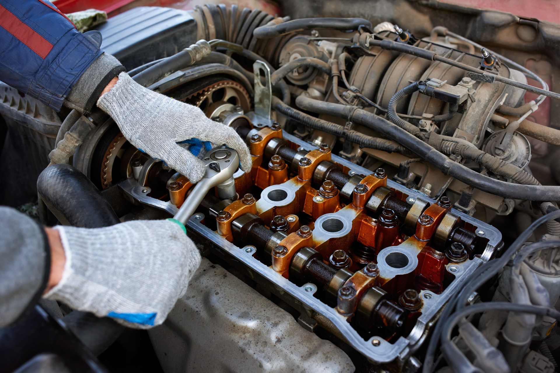 Unscrewing the bolt with a wrench in the engine valve box. Engine with valve cover removed.